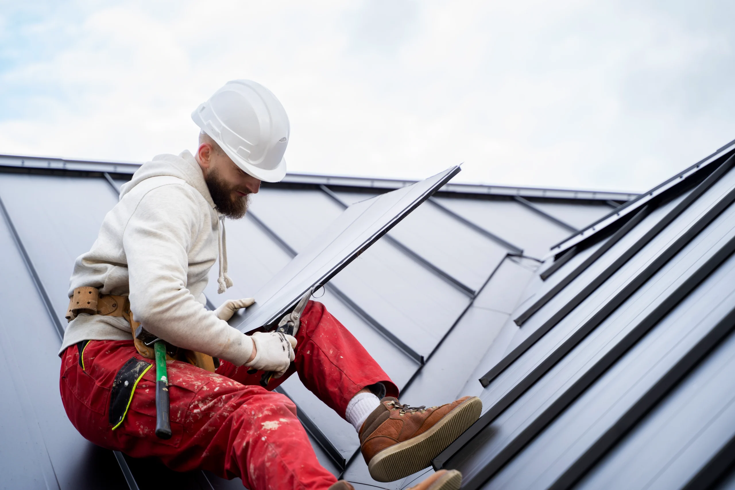 A roofer in safety gear carefully cuts and installs a panel during a Roof Replacement Covington WA.