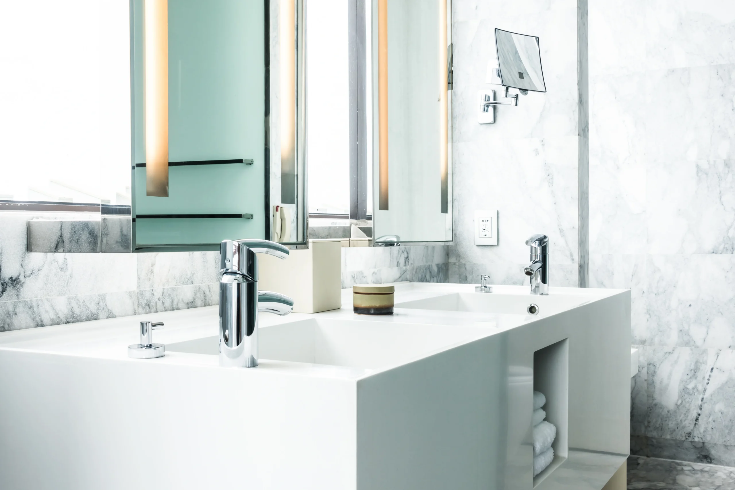 Double modern trough sink, chrome faucets, backlit mirrors, and marble walls define this Bathroom Remodel Covington WA.