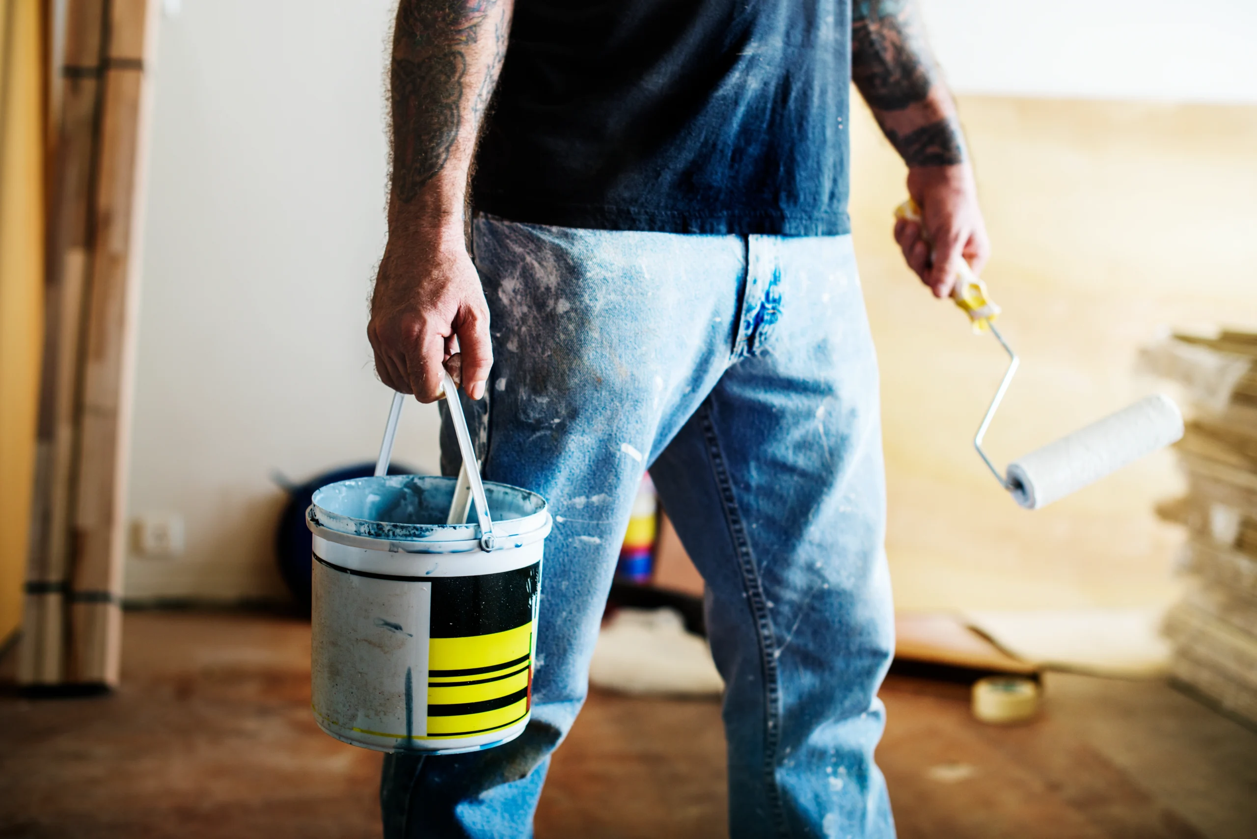 Close-up of a worker holding a paint bucket and roller, ready for Painting Services Covington WA on a renovation site.