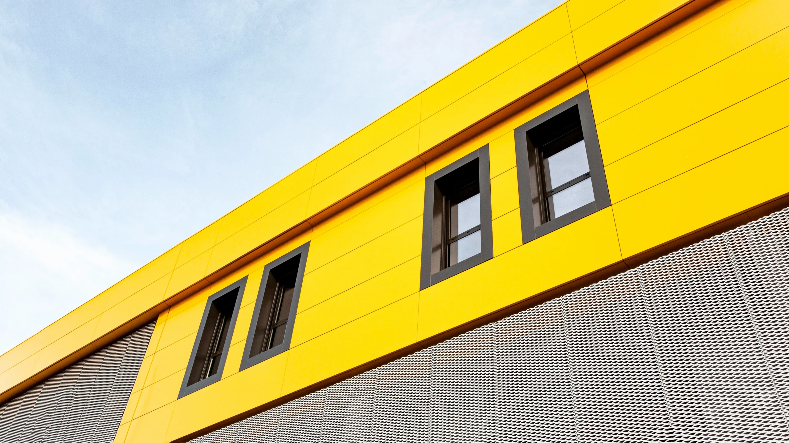 Bright yellow building panels with modern windows installed by a Commercial Exterior Contractor.